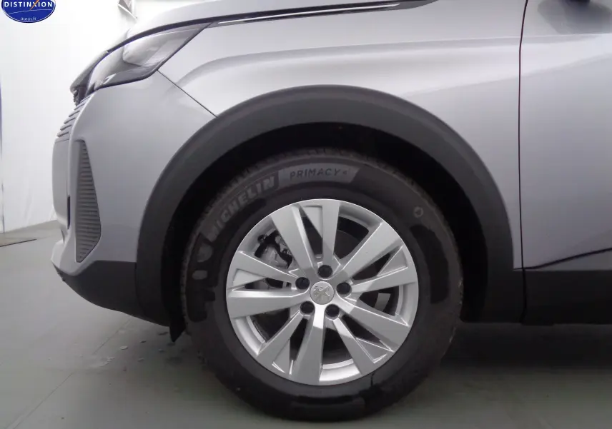 Gros plan sur la roue avant gauche d'un Peugeot 3008 gris Artense métal, avec jante alliage et pneu Michelin.