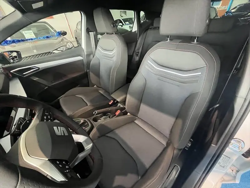 Vue intérieure avant du SEAT Ibiza 2024 avec sièges noirs et volant multifonction au design moderne.