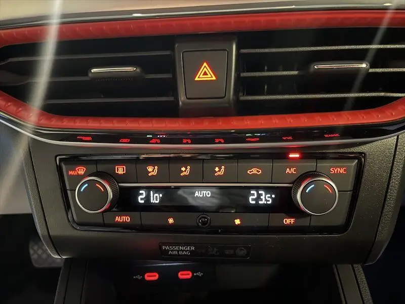 Tableau de bord de la SEAT Ibiza 2024, détail de la climatisation automatique avec réglages numériques et éclairage rouge.