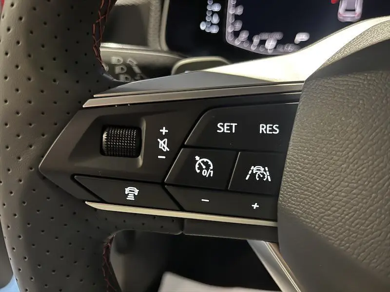 Gros plan sur les commandes du volant en cuir perforé de la SEAT Ibiza 2024 blanc Nevada, avec régulateur de vitesse et assistance active.