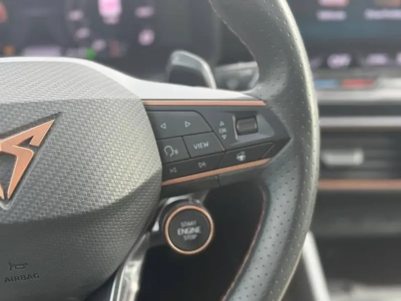 Gros plan sur le volant sport noir perforé avec commandes multifonctions et bouton démarrage du CUPRA Formentor bleu.