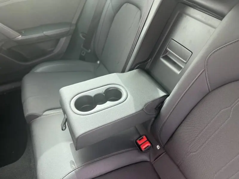 Vue rapprochée de l'accoudoir central arrière avec porte-gobelets sur la banquette textile noire du CUPRA Formentor bleu 2025.