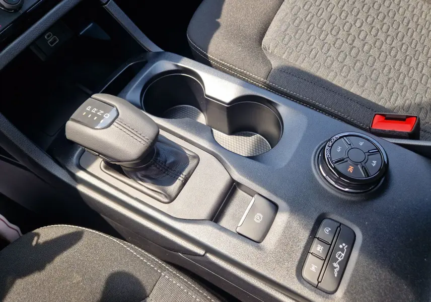 Gros plan sur la console centrale du Ford Ranger Super Cabine gris, montrant levier de vitesse, commandes 4x4 et porte-gobelets.