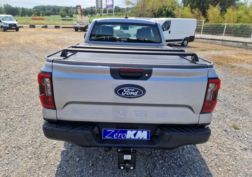 Vue arrière d’un Ford Ranger Super Cabine gris Iconic avec rideau de plateau rigide et attelage visible.