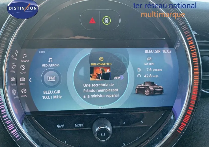 Écran central circulaire de la MINI Cabriolet 2023 en British Racing Green, affichant radio et infos connectées.