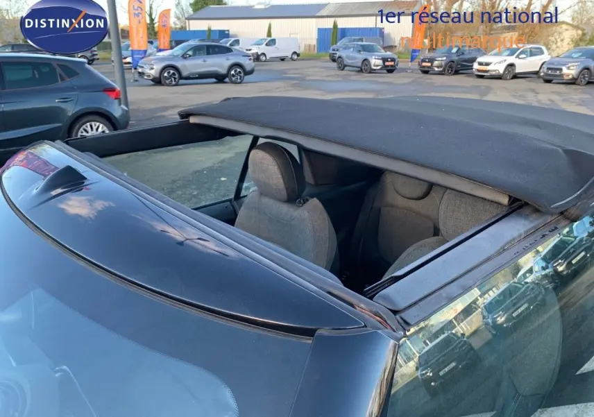 Vue arrière rapprochée d'une MINI Cabriolet British Racing Green avec capote noire partiellement ouverte.