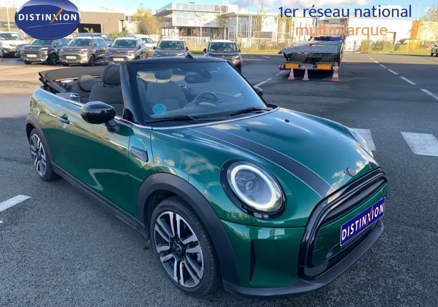 Mini Cabriolet F57 2023 British Racing Green vue 3/4 avant avec capote ouverte et bandes noires sur le capot.