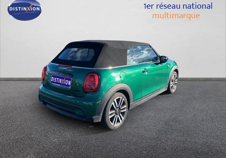 Vue 3/4 arrière droite d'une MINI Cabriolet F57 2023 British Racing Green avec toit souple noir fermé.