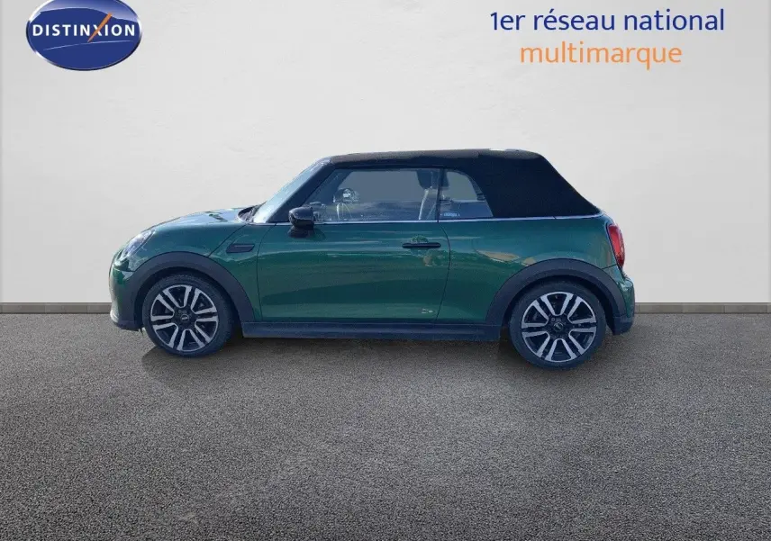 Profil côté gauche d'une MINI Cabriolet 2023 British Racing Green avec toit noir fermé sur fond neutre.