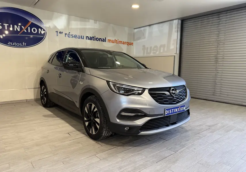 Opel Grandland X gris Himalaya métal vu en 3/4 avant droit dans un showroom avec logo Distinxion visible.