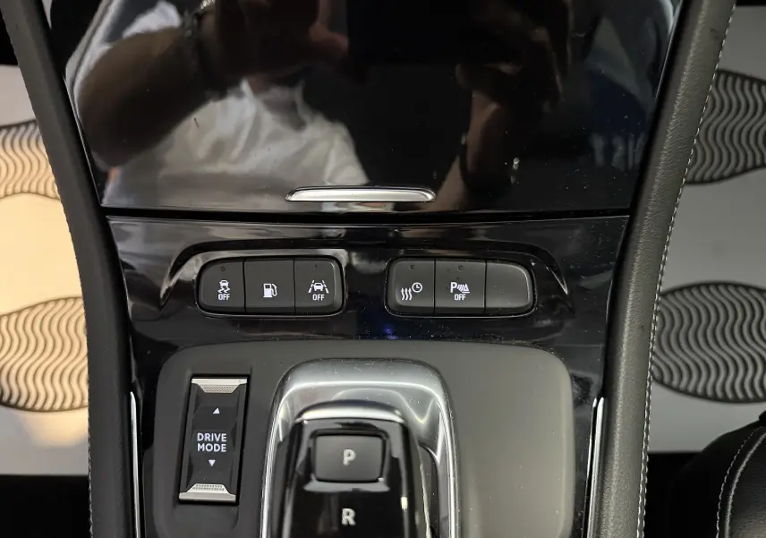 Vue rapprochée de la console centrale noire brillante de l'Opel Grandland X hybride avec sélecteur de mode de conduite.