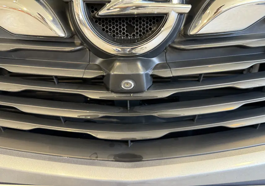 Gros plan sur la calandre gris Himalaya métal de l'Opel Grandland X avec logo et caméra avant intégrée.