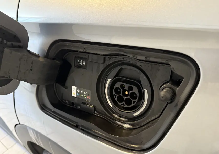 Prise de recharge hybride ouverte côté gauche sur Opel Grandland X gris Himalaya métal, détail du connecteur électrique.