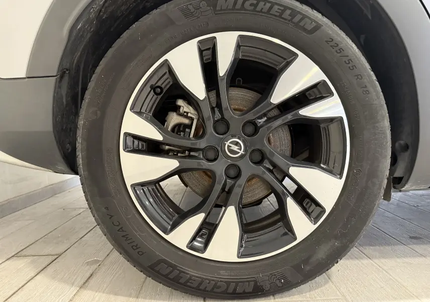 Gros plan sur la jante noire et argentée d’un Opel Grandland X gris Himalaya, mettant en valeur le logo central Opel.