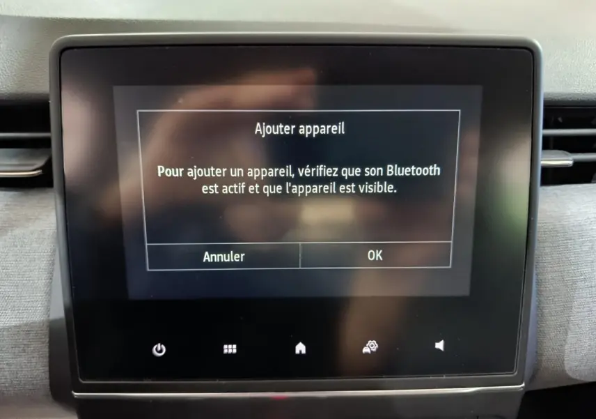 Écran tactile central de la Renault Clio gris clair affichant le message d'ajout d'appareil Bluetooth.