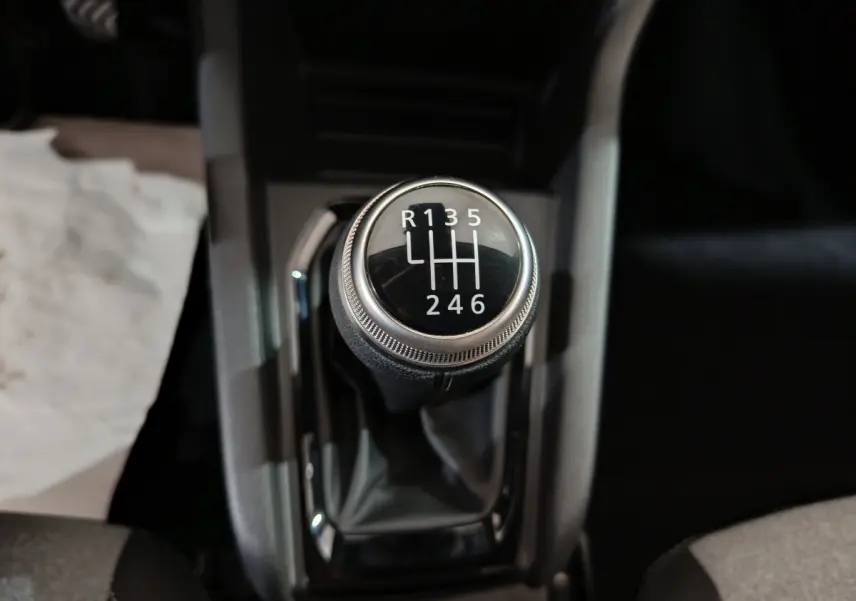 Gros plan sur le levier de vitesses manuel noir de la Renault Clio gris clair, avec marquage des six rapports et marche arrière.