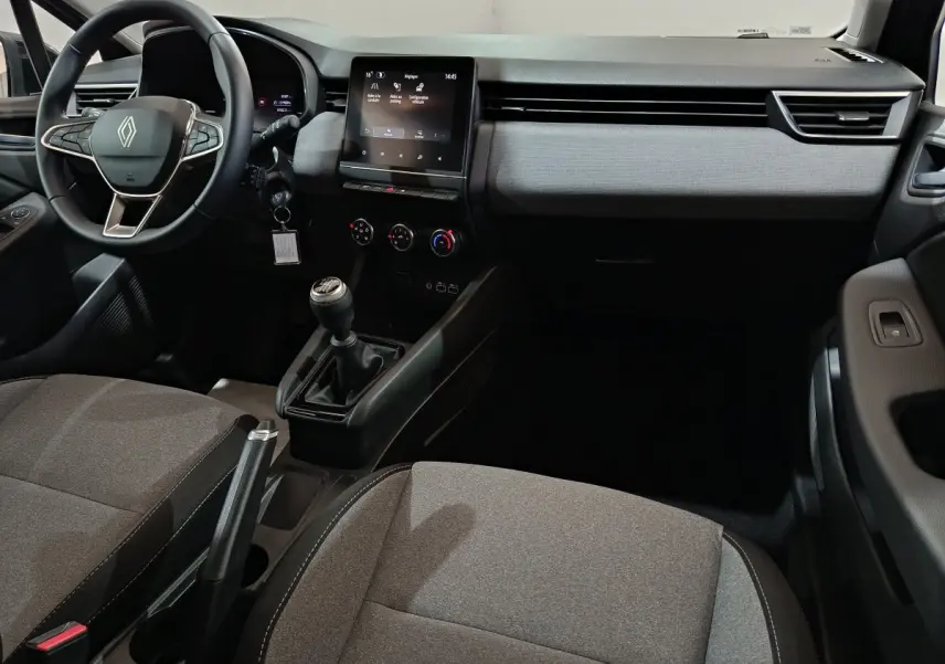 Vue intérieure avant droite de la Renault Clio 2025, tableau de bord gris clair avec écran tactile et volant multifonctions cuir synthétique.