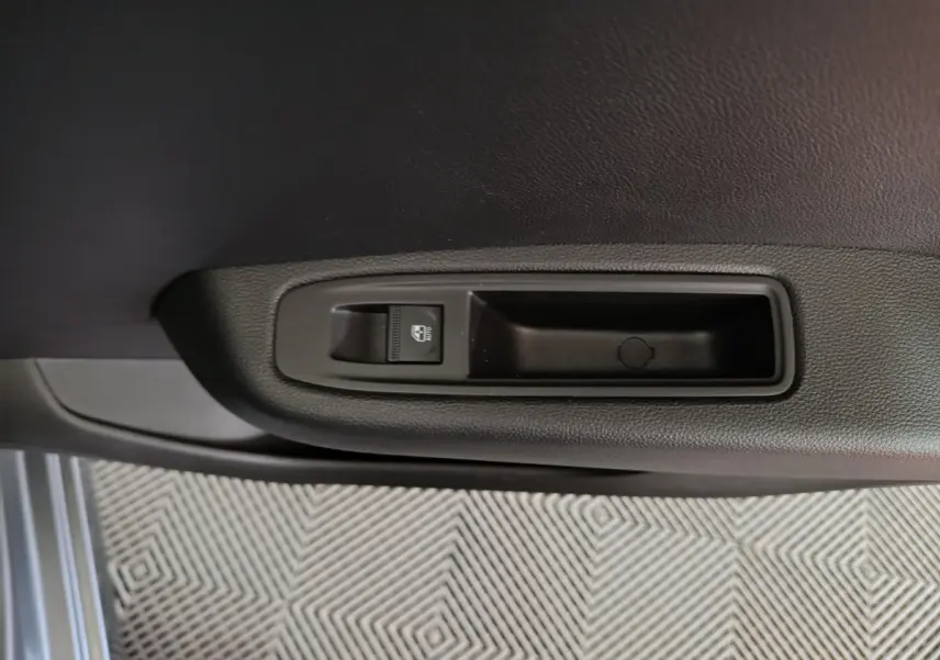 Gros plan sur la commande de lève-vitre côté porte intérieure d’une Renault Clio gris clair, version Evolution Blue dCi 100 -25.