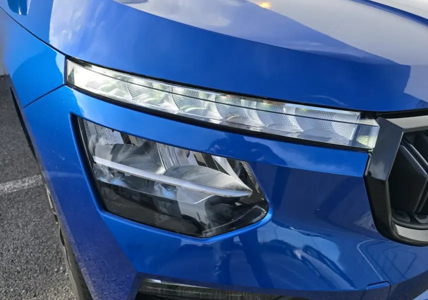 Gros plan sur le phare avant gauche du Skoda Kamiq 2025 bleu racing avec toit noir, mettant en valeur ses feux LED distinctifs.