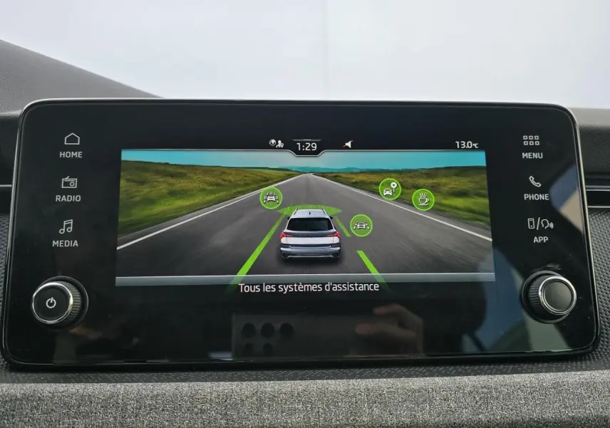 Écran central affichant l'assistance à la conduite avec vue arrière d'une Skoda Kamiq bleu racing et toit noir.