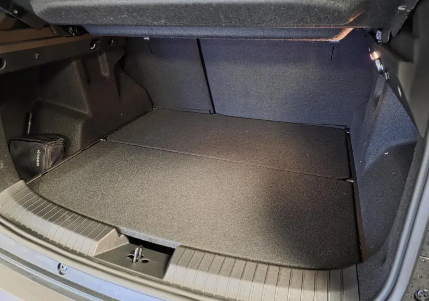 Coffre ouvert du Dacia Duster 1.6 Hybrid noir, vue plongeante montrant l’espace de rangement et la moquette noire.