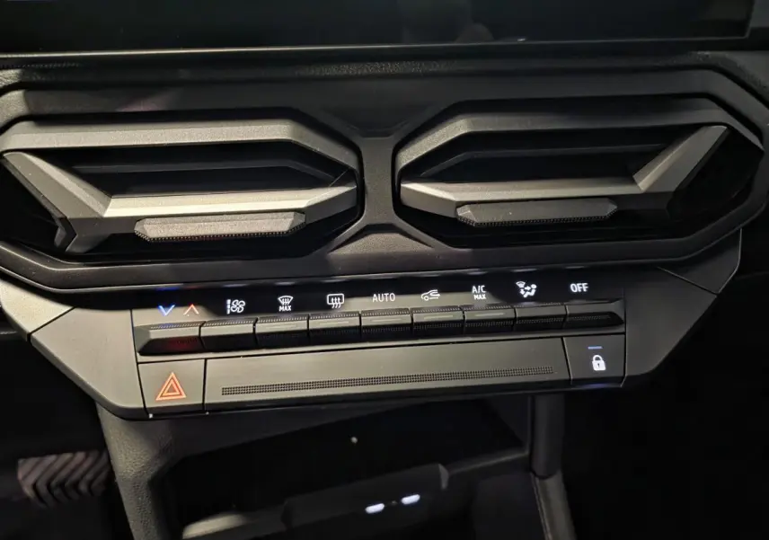 Détail des aérateurs gris acier et commandes climatisation du tableau de bord du Dacia Duster noir 2025.