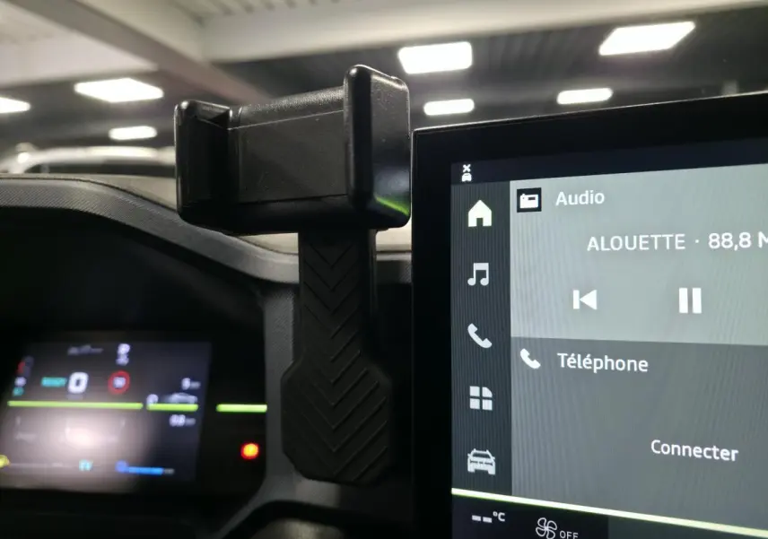 Vue intérieure rapprochée du support smartphone fixé près de l’écran tactile central du Dacia Duster 1.6 Hybrid noir.