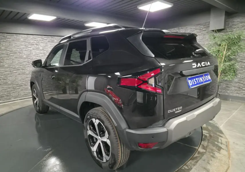 Vue 3/4 arrière droite du Dacia Duster 1.6 Hybrid noir nacré avec jantes alliage et barres de toit noires.