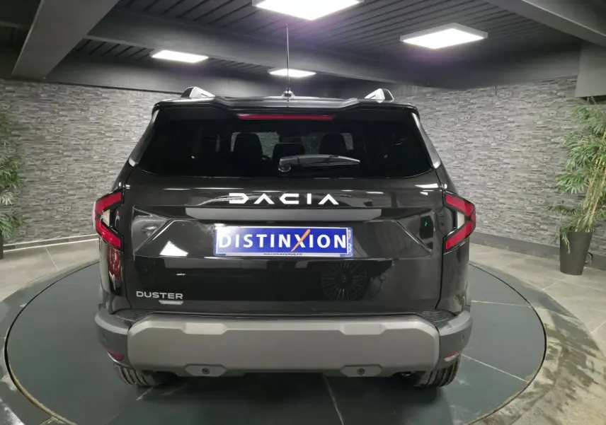 Vue arrière d'un Dacia Duster noir nacré 2025 avec logo DACIA inversé et plaque Distinxion.