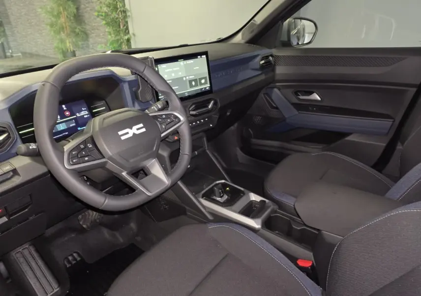 Vue intérieure côté conducteur du Dacia Duster 1.6 Hybrid 2025, tableau de bord et volant noir avec inserts Denim Bleu.