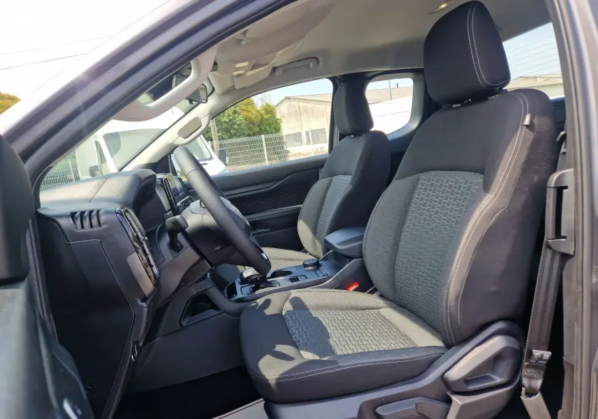 Vue intérieure côté conducteur du Ford Ranger Super Cabine 2026, sièges tissu gris avec console centrale et volant visibles.