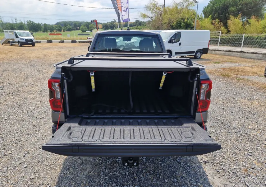 Vue arrière du Ford Ranger Super Cabine gris carbone avec plateau ouvert et rideau rigide coulissant visible.