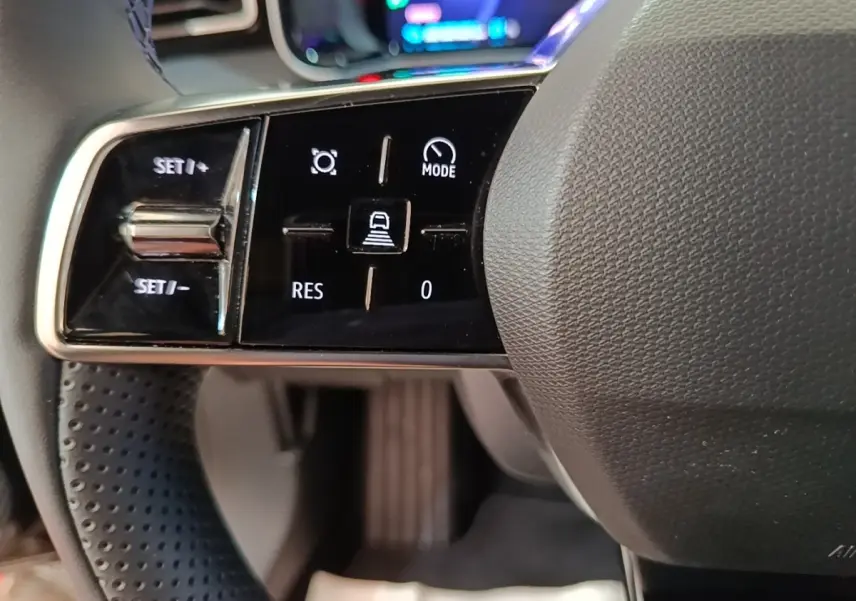 Gros plan sur les commandes noires et chromées du volant de la Renault R5 électrique 2024, côté gauche.