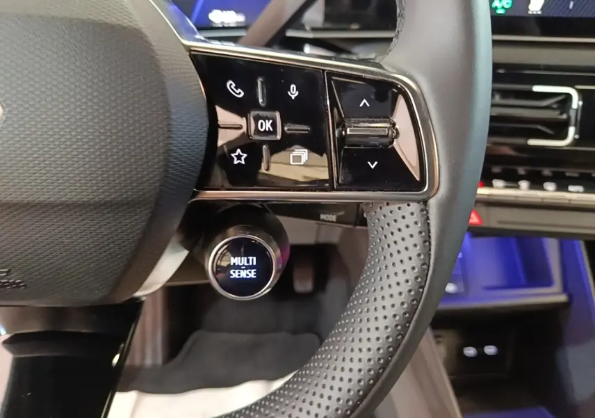 Gros plan sur le volant perforé et les commandes tactiles du Renault R5 électrique 2024, ambiance intérieure moderne.
