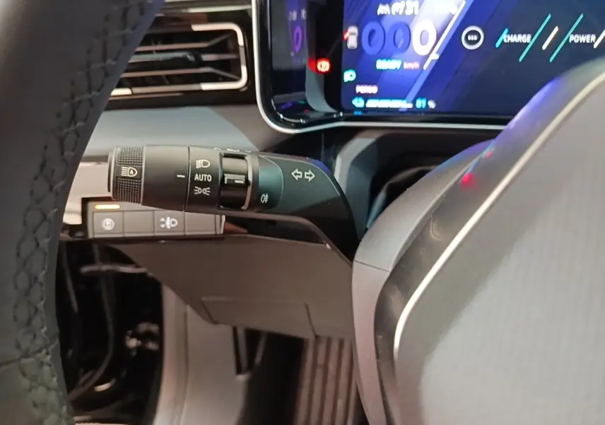 Vue intérieure rapprochée du combiné d'instruments numérique et commande des phares sur Renault R5 Iconic 2024, tableau de bord noir.