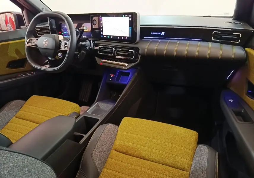 Vue intérieure avant droite de la Renault R5 Iconic 2024 avec sièges moutarde et tableau de bord numérique.