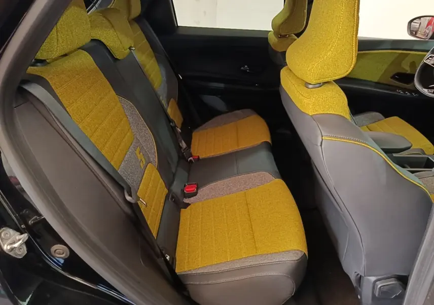 Vue intérieure côté gauche montrant les sièges arrière jaunes et gris du Renault R5 Iconic 2024 avec détails textiles.