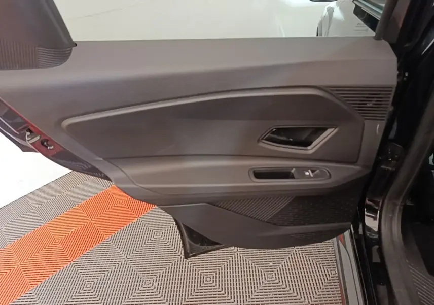 Vue rapprochée de la porte arrière droite noire de la Renault R5 électrique 2024, avec poignée et commande de fenêtre.