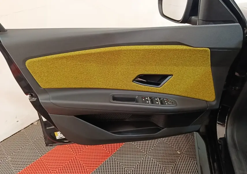 Vue latérale de la porte avant droite de la Renault R5 2024 avec panneau intérieur jaune et commandes électriques.