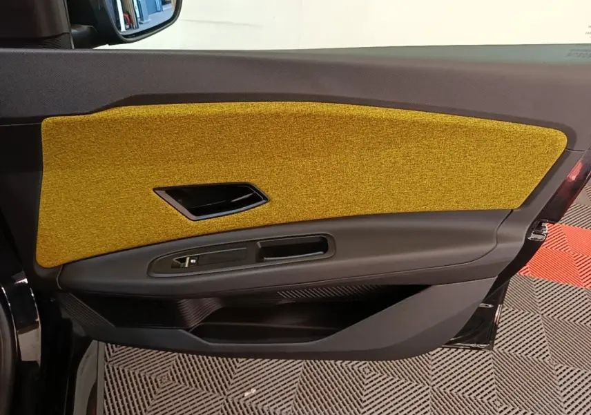 Vue intérieure côté gauche de la porte avant Renault R5 2024 avec insert textile jaune moutarde et garniture noire.