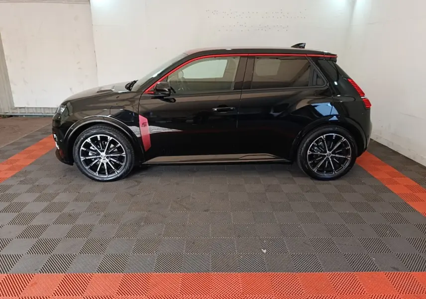 Profil gauche d'une Renault R5 Iconic électrique noire avec détails rouges et jantes noires stylisées.
