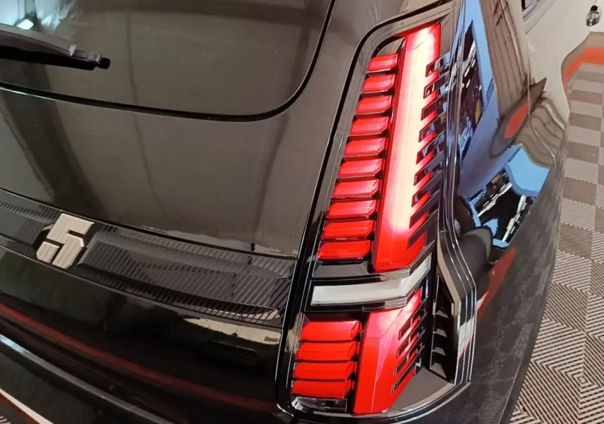 Gros plan sur le feu arrière droit rouge et noir de la Renault R5 Iconic électrique 2024 couleur sombre.