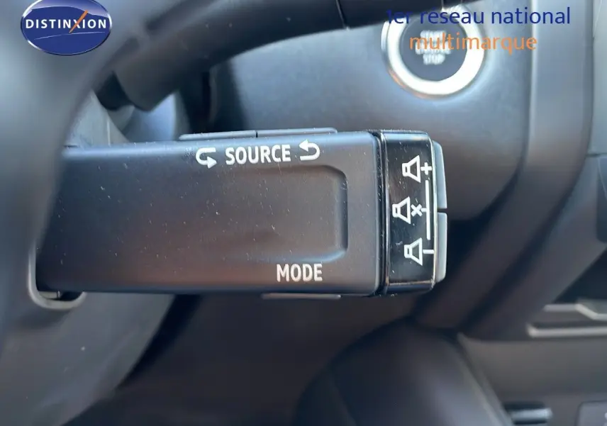 Gros plan sur la commande au volant du Renault Captur blanc nacré, mettant en valeur les boutons source et mode.