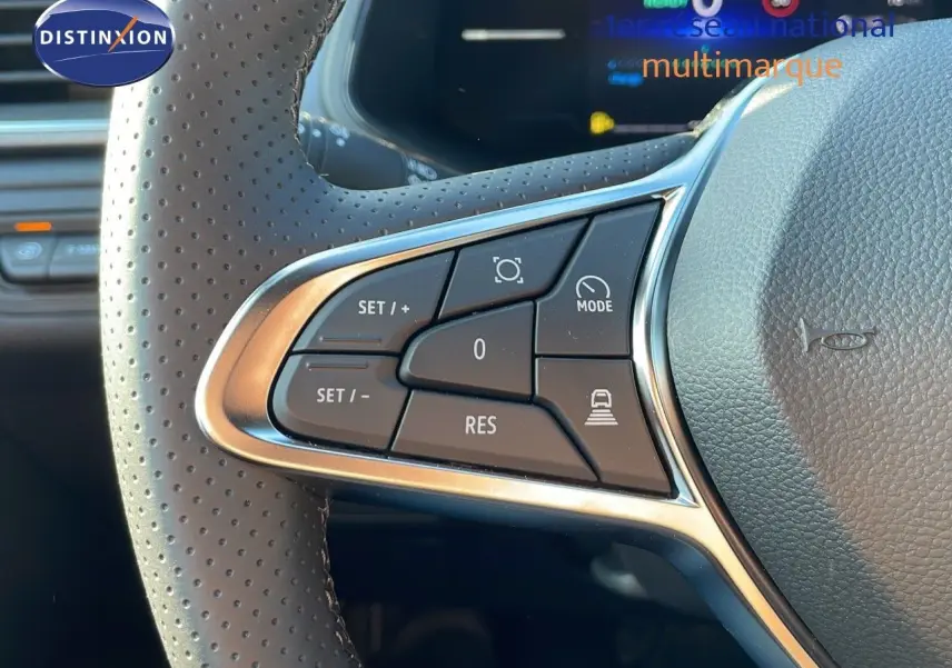 Gros plan sur les commandes au volant du Renault Captur blanc nacré 2025, mettant en valeur les boutons multifonctions.