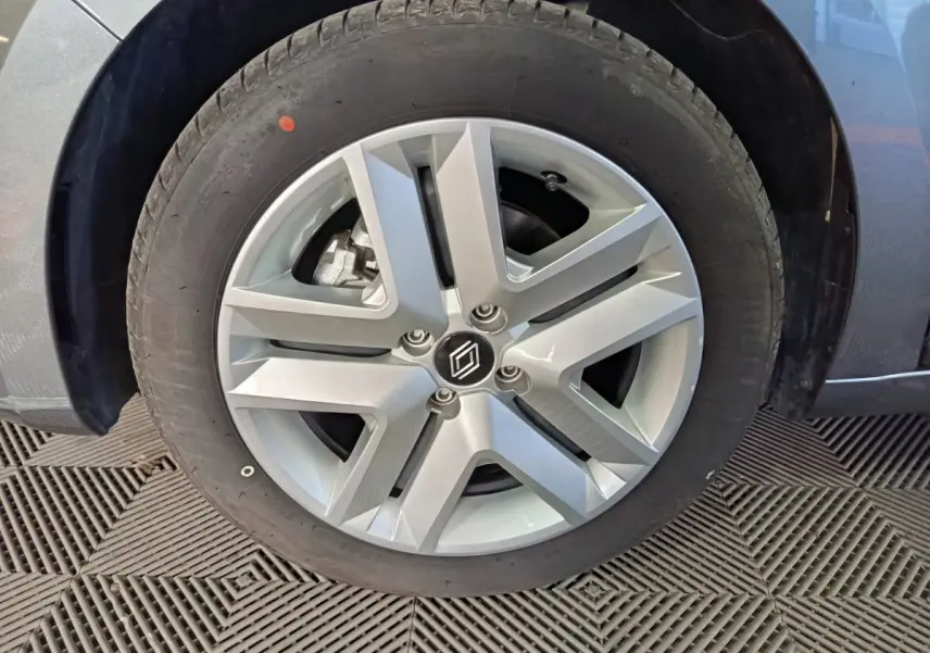 Gros plan sur la roue avant gauche de la Renault Clio gris clair avec jante alliage au design moderne.