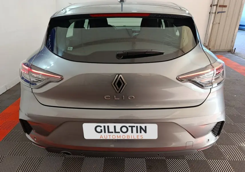 Vue arrière d'une Renault Clio gris clair 2025 avec feux LED et logo centré dans un garage.