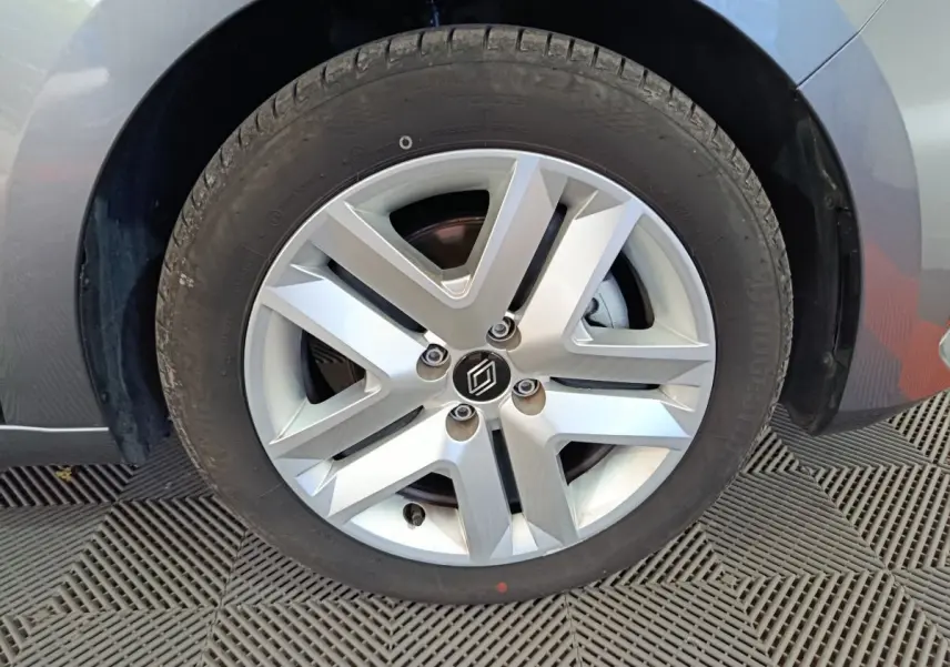 Gros plan sur la roue avant gauche d’une Renault Clio gris clair, avec jante alliage à design moderne.