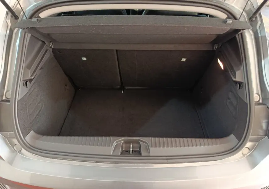 Coffre ouvert vu de l'arrière d'une Renault Clio gris clair, montrant l'espace de chargement vide et la tablette arrière.