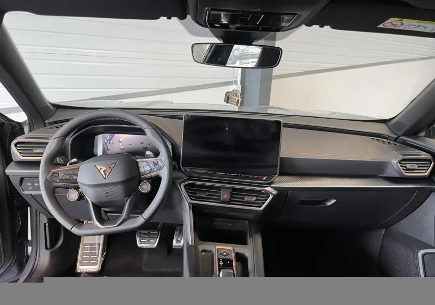 Vue avant de l'habitacle du CUPRA Formentor gris clair, volant cuir, écran tactile central et finitions cuivrées.