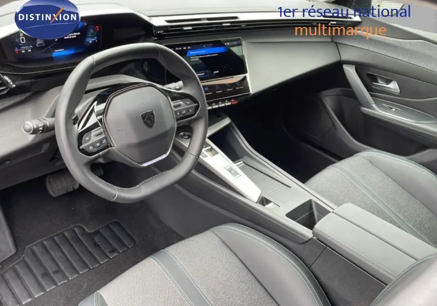 Vue intérieure côté conducteur du Peugeot 408 1.2 Hybrid 145ch Allure, avec volant multifonction et sellerie gris noir.
